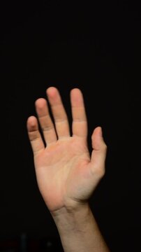 Man waving his hand on a black background greeting someone when meeting.
Friendly and happy man waving his hand.
Meeting guests and joy.
Meeting, waving, friendly, male