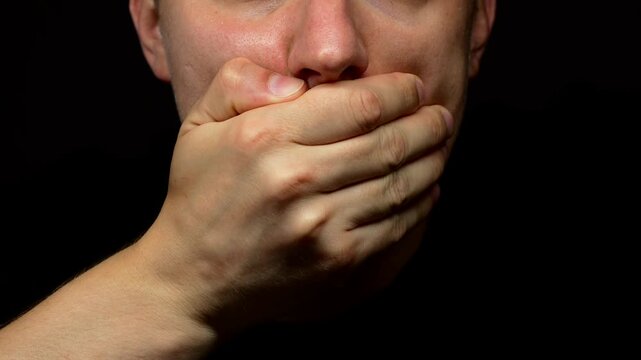 A man covers his mouth with his hands, keeping a secret or important information.
A man covers his mouth with his palms and is silent.
Silence and quiet.
Mouth, close, secret, keep, lips
