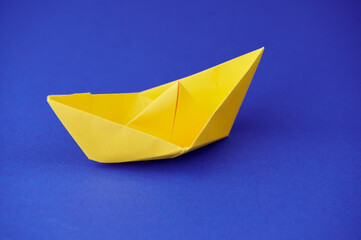 Bright yellow origami boat on a blue background showcasing creativity