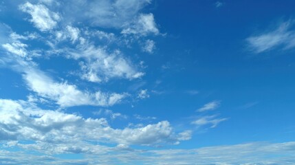 Obraz premium A clear sky showcases a vibrant blue backdrop filled with cotton-like white clouds, reflecting the warmth of a sunny afternoon, perfect for outdoor activities.