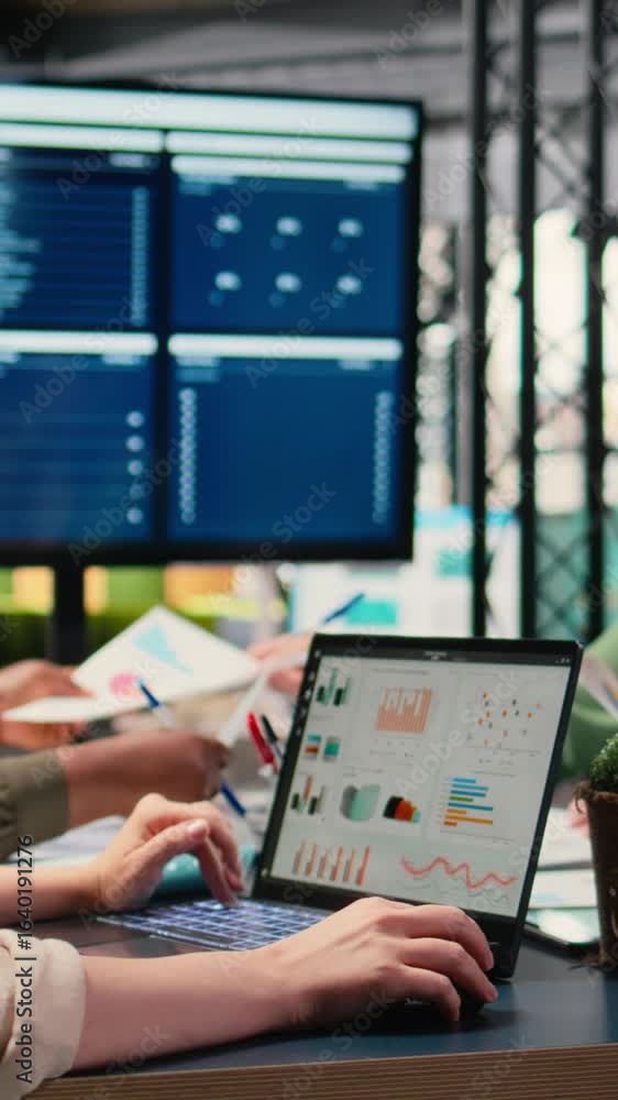 Poster vertical video focused businesswoman analyzing graphs and data on laptop at the table, working with 