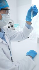 Medical science researcher wearing blue protective gear of cap, gloves and googles, is examining...