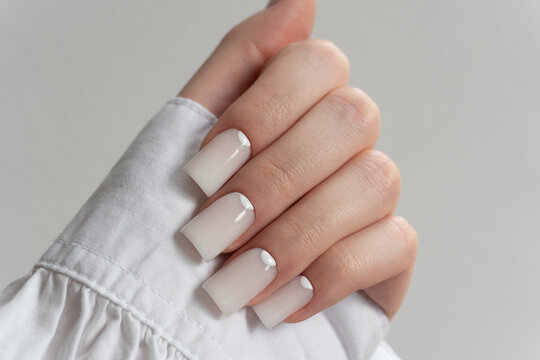 Glossy white manicure – elegant long nails with smooth polish, minimal chic nail art design. The thumb and fingertips are slightly rounded, showcasing an elegant style. 
