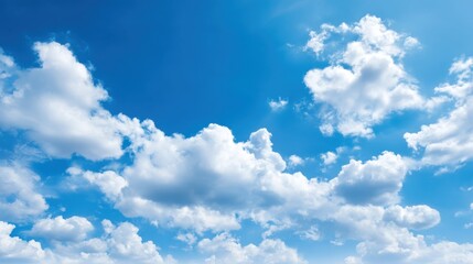 Fototapeta premium Fluffy white clouds float gently in a vibrant blue sky, creating a serene atmosphere. The sun shines brightly, adding warmth to the inviting scene.