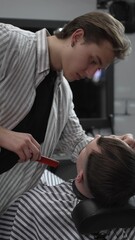 Professional barber trimming customer's hair with electric clipper, focusing on precise nape...
