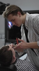 Professional barber trimming customer's hair with electric clipper, focusing on precise nape...