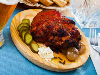 Appetizing pork knuckle served with boiled onions and pickled cucumbers