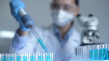Close up of a female scientist researcher hand using a micropipette to fill up test tubes with a...
