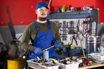 Portrait of professional auto mechanic in uniform with tools in his hands in a car service center