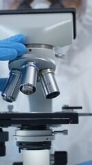 Close up of medical virologist in a hazmat suit, mask, and gloves, diligently working at a microscope in a laboratory researching viruses. Medicine and science concept