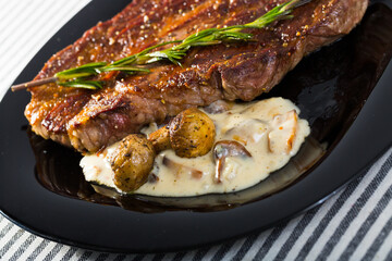 Image of beef entrecote with mushroom sauce on the plate indoors.