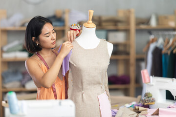 Female tailor sews new dress on a mannequin in a sewing studio