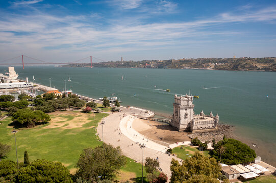 Aerial drone view of Belem Tower, the old gateway to Lisbon, with 25 de Abril Bridge in the background. Historic UNESCO landmark on the Tagus River, Portugal 