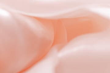 Abstract close-up of silky flowing shapes in peach and pink tones, with smooth curves and glossy...