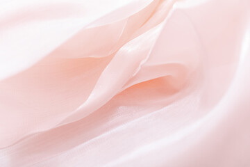 Close-up of soft flowing pink fabric with delicate folds and translucent texture, ideal for...