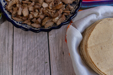 Top view of a wooden table with a portion of pork carnitas and tortillas, everything you need for tacos, Mexican food, space for text