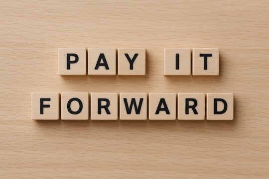 Pay It Forward Message Spelled Out With Wooden Blocks on Textured Beige Background