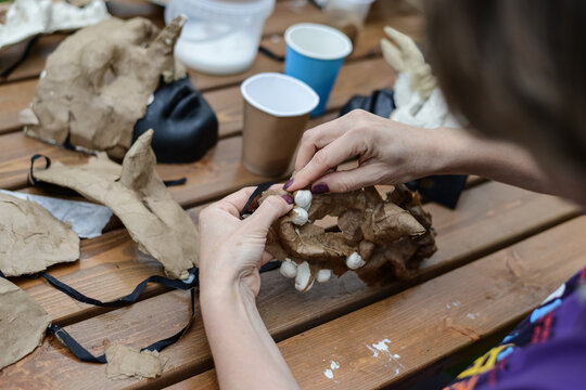 Crafting hands outdoor. Close photo of handmade paper sculpting masks. A woman's hands make a mask from papier mache at the table. The street is a summer day park. High quality photo