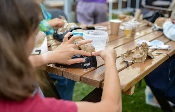 Children are engaged in face sculpture on a special mask. artistic modeling of theatrical masks. Girl sculpting papiermache theatrical mask with her hands at a table outside in the summer. 