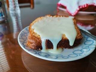 Slice of freshly baked homemade vanilla cake, served as dessert with a topping of condensed milk,...