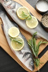 Fresh raw seabass with spices on black table, top view. Fish and seafood delicacies