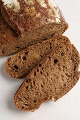 Pieces of fresh rye bread on white textured table, above view