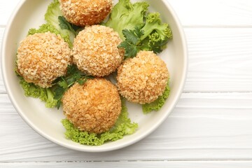 Delicious fried croquette balls with parsley and lettuce on white wooden table, top view