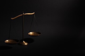 Golden scales of justice on black background, space for text