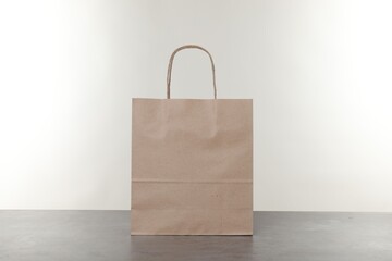 One kraft paper bag on grey table against white background