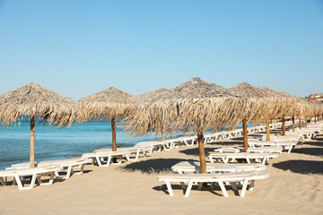 Straw umbrellas and sunbeds on sandy beach