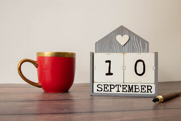 Wooden calendar organizer with date September 10 on table.