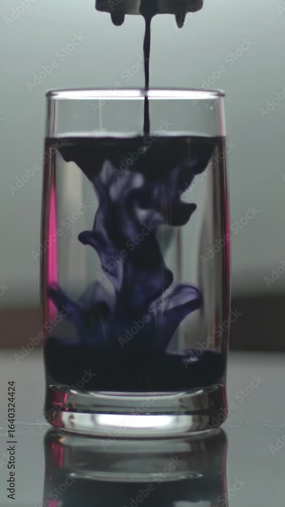 Aufkleber black ink dropping into a glass of clear water creating an abstract and mesmerizing display in a dar