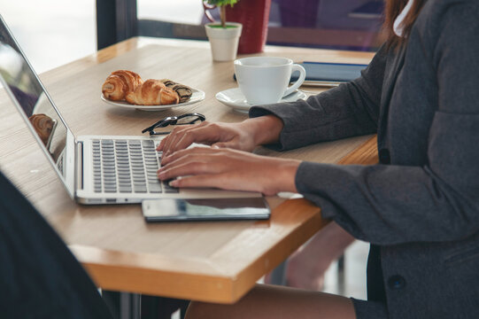 Close up businesswoman hand typing laptop drink black coffee cup in green garden cafe. Woman Hands love drinking hot coffee working from home. Business women with black coffee or hot chocolate cafe - Powered by Adobe