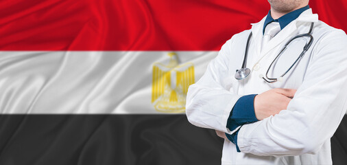 Egypt healthcare concept. Male doctor on Egypt flag. Doctor with crossed arms on Egypt flag