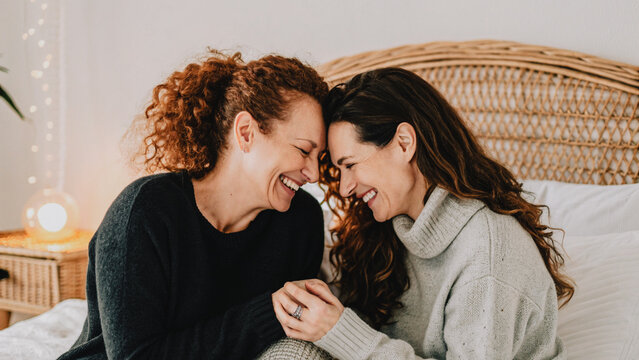 Mature lesbian couple engaged holding hands smiling in bedroom background gay LGBT love concept - AI generative model