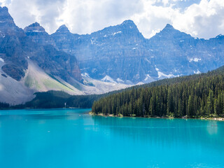 Turquoise Moraine Lake with pine forest and rugged mountain peaks