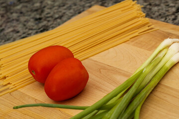 Uncooked Pasta and Fresh Vegetables on Wooden Cutting Board for Meal Prep