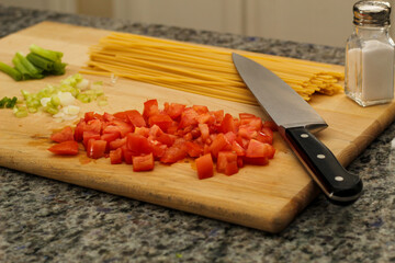 Uncooked Pasta and Fresh Vegetables on Wooden Cutting Board for Meal Prep