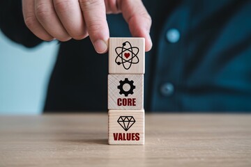 Hand stacking wooden blocks with core values icons, business ethics, company culture and mission concept.