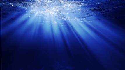Sunlight streams through ocean waves, creating a mesmerizing play of light and shadow in deep blue waters.