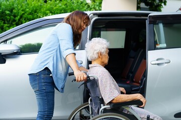 Caregiver help Asian elderly woman disability patient use wheelchair to get in car.