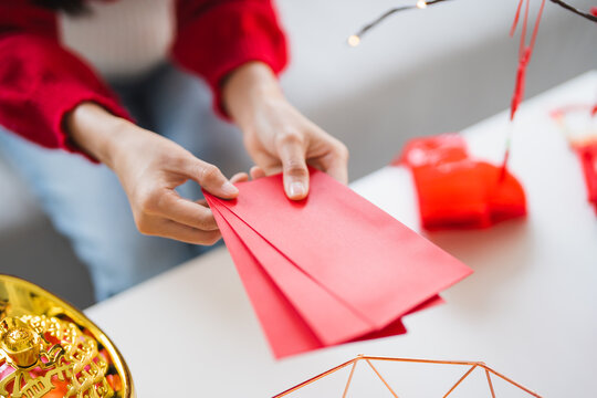 Asian Woman giving red envelope for Lunar New Year celebrations. Hand hold red packet