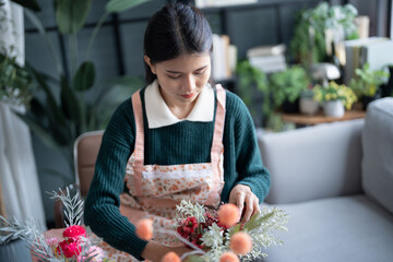 Happy asian Woman arranging flowers caring for home greenery