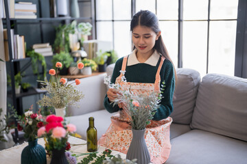 Happy asian Woman arranging flowers caring for home greenery