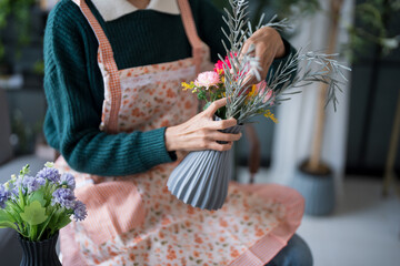 Happy asian Woman arranging flowers caring for home greenery