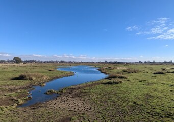 Open waterway through grassy plains under a vibrant blue sky