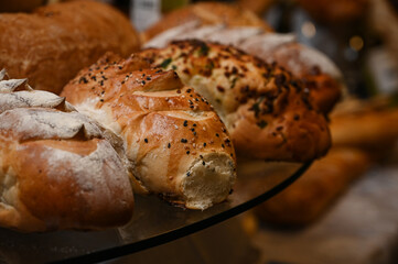 fresh bread assortment with melted cheese fondue, bakery display with cheese wheel, artisan bread and cheese platter,bread with sesame seeds, assorted breads, bread display
