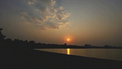 Fototapeta premium Sunset over a tranquil lake with a city skyline.