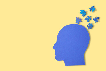 Blue head silhouette with puzzle pieces on yellow background