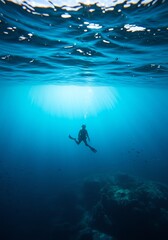 Naklejka premium Scuba Diver Swimming Underwater in Blue Ocean Scene with Sunlight Rays